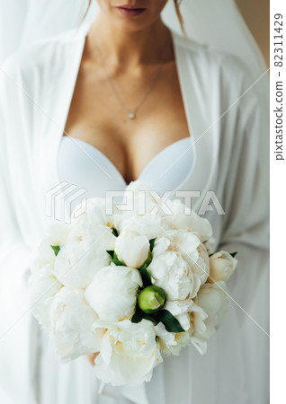morning of the bride in the hotel room. slightly blurred image of a bouquet in the hands. 82311429