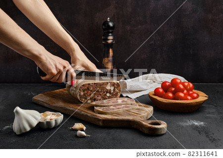 Female hand with a knife cuts boiled pork roll Female hand with a knife cuts boiled pork roll 82311641