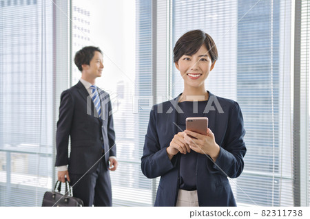 Business person looking at a smartphone in the office Business person looking at a smartphone in the office 82311738