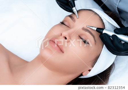 Cosmetology. Beautiful Woman At Spa Clinic Receiving Stimulating Electric Facial Treatment From Therapist. Closeup Of Young Female Face During Microcurrent Therapy 82312354