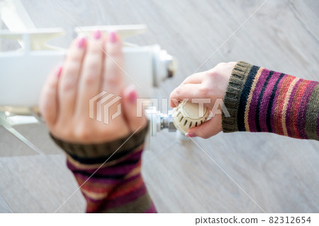 Radiator adjustment closeup. Female hand adjusting radiator temperature 82312654