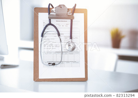 Stethoscope and clipboard with medication history records are on the table at sunny doctor's working place. Medicine concept 82313294