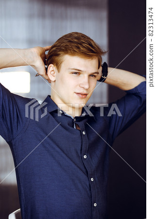 Young blond businessman and programmer stretching hands after working hard with computer. Startup business leads to success 82313474
