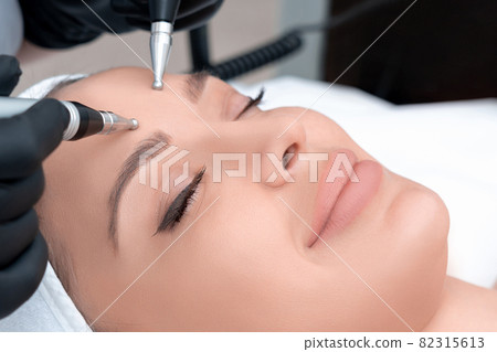 Cosmetology. Beautiful Woman At Spa Clinic Receiving Stimulating Electric Facial Treatment From Therapist. Closeup Of Young Female Face During Microcurrent Therapy Cosmetology. Beautiful Woman At Spa Clinic Receiving Stimulating Electric Facial Treatment From Therapist. Closeup Of Young Female Face During Microcurrent Therapy 82315613