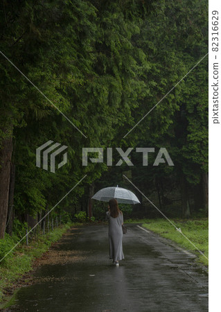 一個女人在下雨天拿著傘走路的背影 82316629