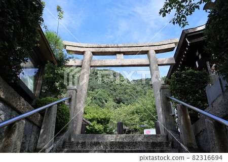 A landscape of green trees and mountains over the blue sky, white clouds and stone torii gates 82316694