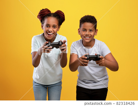 Joyful black brother and sister holding joysticks 82318426