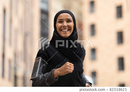 Portrait Of Happy Young Islamic Lady In Hijab Jogging Outdoors Portrait Of Happy Young Islamic Lady In Hijab Jogging Outdoors 82318621