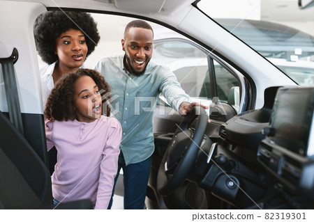 Excited black family looking into car salon, selecting new automobile at dealership, copy space Excited black family looking into car salon, selecting new automobile at dealership, copy space 82319301