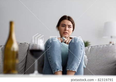 Unhappy sorrowful cute young european lady sad from problems with alcohol at home interior Unhappy sorrowful cute young european lady sad from problems with alcohol at home interior 82319791