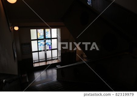 Focus on the window with stained glass on the stairs of the closed school facility and take a picture 82319979