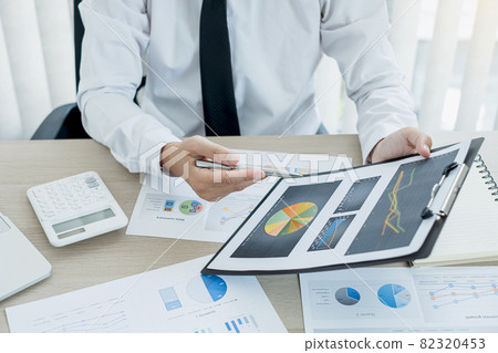 The businessman hand sits at their desks and calculates financial graphs showing the results of their investments planning the process of successful business growth The businessman hand sits at their desks and calculates financial graphs showing the results of their investments planning the process of successful business growth 82320453