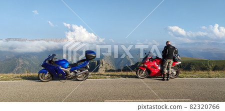 Traveller and motorcycles on road 82320766