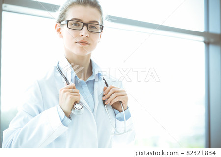 Beautiful woman doctor with stethoscope smiling charmingly and ready to help patients in the modern hospital. Medicine concept 82321834