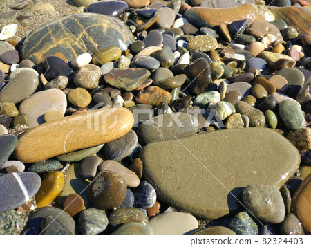 Sea stones background of the many beautiful colored stones, sunshine. 82324403