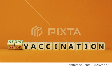 Start vaccination symbol. Turned wooden cubes and changed words 'stop vaccination' to 'start vaccination'. Beautiful orange background, copy space. Medical and covid-19 pandemic concept. Start vaccination symbol. Turned wooden cubes and changed words 'stop vaccination' to 'start vaccination'. Beautiful orange background, copy space. Medical and covid-19 pandemic concept. 82324432