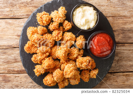 Portion of homemade snack Chicken popcorn with two sauces close-up on a slate board. horizontal top view 82325034