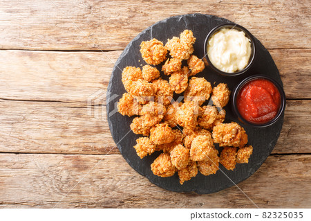 Crispy Chicken Popcorn with Tomato Ketchup and mayonnaise closeup in the slate dish. Horizontal top view Crispy Chicken Popcorn with Tomato Ketchup and mayonnaise closeup in the slate dish. Horizontal top view 82325035