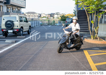一個戴著面具騎著滑板車的女人 82325716