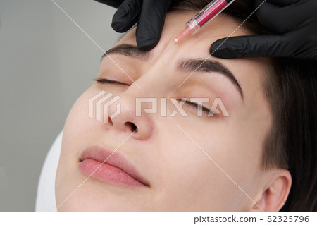 Beautiful woman gets an injection in her face 82325796