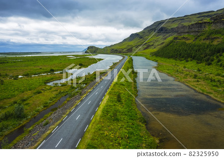 Iceland. Aerial view on mountain, field and river. Landscape in Iceland at the day time. View from drone. Summer. Cloudy weather. Fresh grass on field. Travel and vacation image 82325950