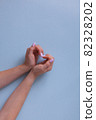 Stylish pink manicure on a blue background with place for text. Hands are folded in a heart. 82328202
