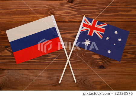 The flag of Russia and the flag of Australia are crossed with each other on a brown background with a wood texture. Top view. Close Up The flag of Russia and the flag of Australia are crossed with each other on a brown background with a wood texture. Top view. Close Up 82328576