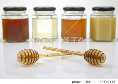 Hexagonal jars with different types and colors of fresh flower honey and a honey spoon 82329435