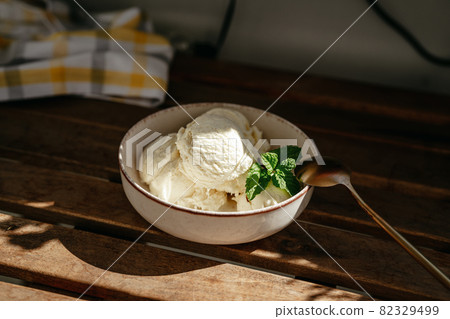 Bowl of vanilla ice cream on wooden table outdoors Bowl of vanilla ice cream on wooden table outdoors 82329499
