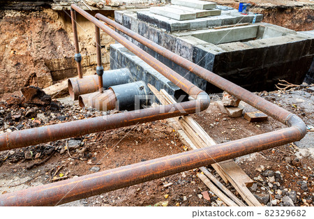 Construction works on large iron pipes at a depth of excavated trench 82329682
