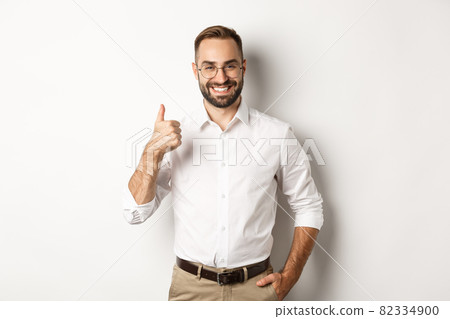 Satisfied successful boss showing thumb up, approve and praise good work, standing over white background 82334900