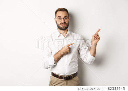 Doubtful and worried man looking indecisive, pointing at upper right corner hesitant, standing over white background Doubtful and worried man looking indecisive, pointing at upper right corner hesitant, standing over white background 82335645