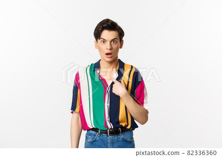 Surprised man pointing at himself and looking confused, standing over white background 82336360
