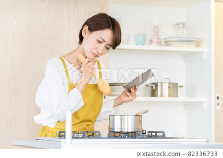 Middle woman cooking while looking at a tablet 82336733