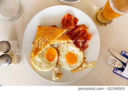 Fried eggs, roasted bacon slices and wheat bread toasts 82340003