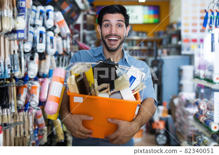 Satisfied guy handyman holding basket with tools 82340051