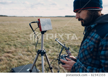 Man pilot controlling quadcopter drone with remote controller pad 82341333