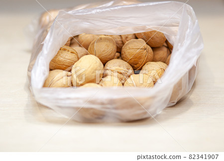 A lot of whole walnuts in a bag on a white background. Healthy, organic food with a high content of protein and protein. 82341907