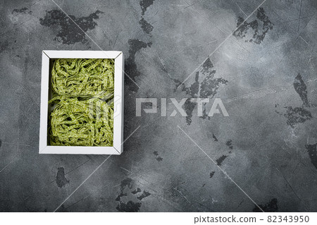 Raw green pasta pack, on gray stone table background, top view flat lay, with copy space for text Raw green pasta pack, on gray stone table background, top view flat lay, with copy space for text 82343950