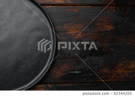 Top view of black plate, on old dark wooden table background 82344205
