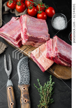 Raw veal calf short rib meat, with ingredients , on black stone background 82344691