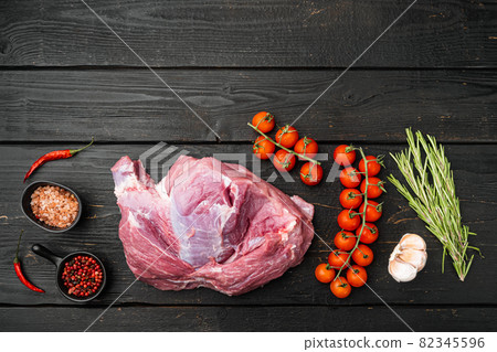 Raw meat, piece of pork with seasonings, on black wooden table background, top view flat lay, with copy space for text 82345596