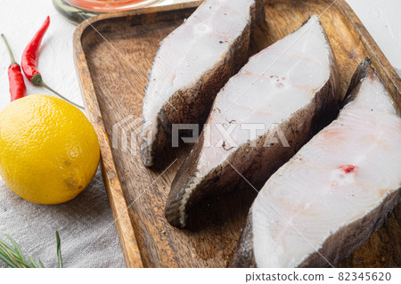Raw fish steak, with ingredients and rosemary herbs, on white stone table background Raw fish steak, with ingredients and rosemary herbs, on white stone table background 82345620