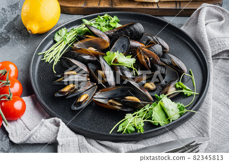 Boiled mussels in garlic sauce with parsley and ingredients, on plate, on gray background Boiled mussels in garlic sauce with parsley and ingredients, on plate, on gray background 82345813