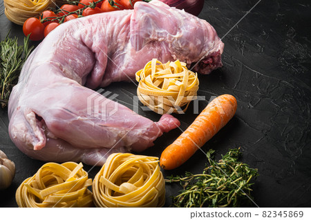Raw rabbit meat and cooking ingredients stew tagliatelle, on black stone background, with copy space for text Raw rabbit meat and cooking ingredients stew tagliatelle, on black stone background, with copy space for text 82345869