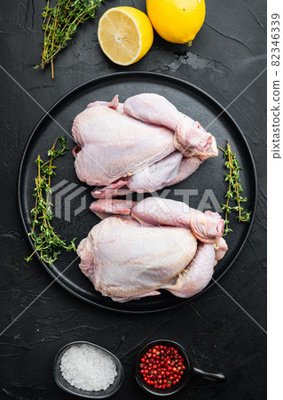 Raw organic uncooked whole chicken with herbs spices ingredients, on black background, top view Raw organic uncooked whole chicken with herbs spices ingredients, on black background, top view 82346339