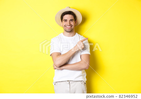 Young male tourist pointing finger right, smiling and showing advertisement, concept of tourism and lifestyle, yellow background 82346952