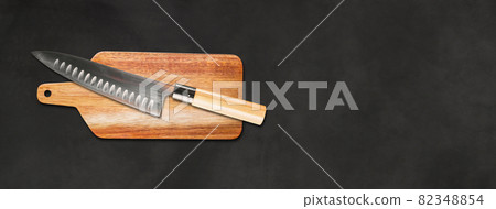 Traditional Japanese gyuto chief knife on a cutting board. Black concrete background banner Traditional Japanese gyuto chief knife on a cutting board. Black concrete background banner 82348854