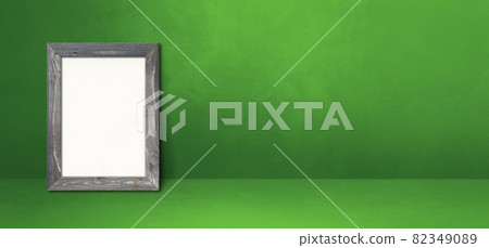 Wooden picture frame leaning on a green wall. Horizontal banner 82349089