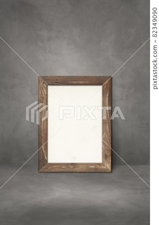Wooden picture frame leaning on a dark concrete wall 82349090